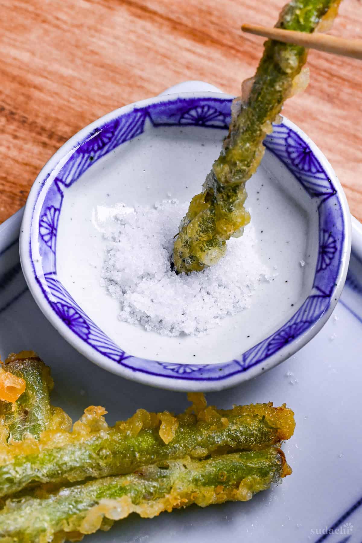 dipping asparagus tempura in salt close up