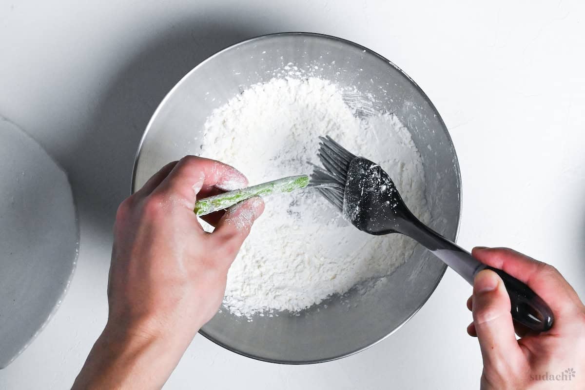 brushing asparagus with flour using a pastry brush
