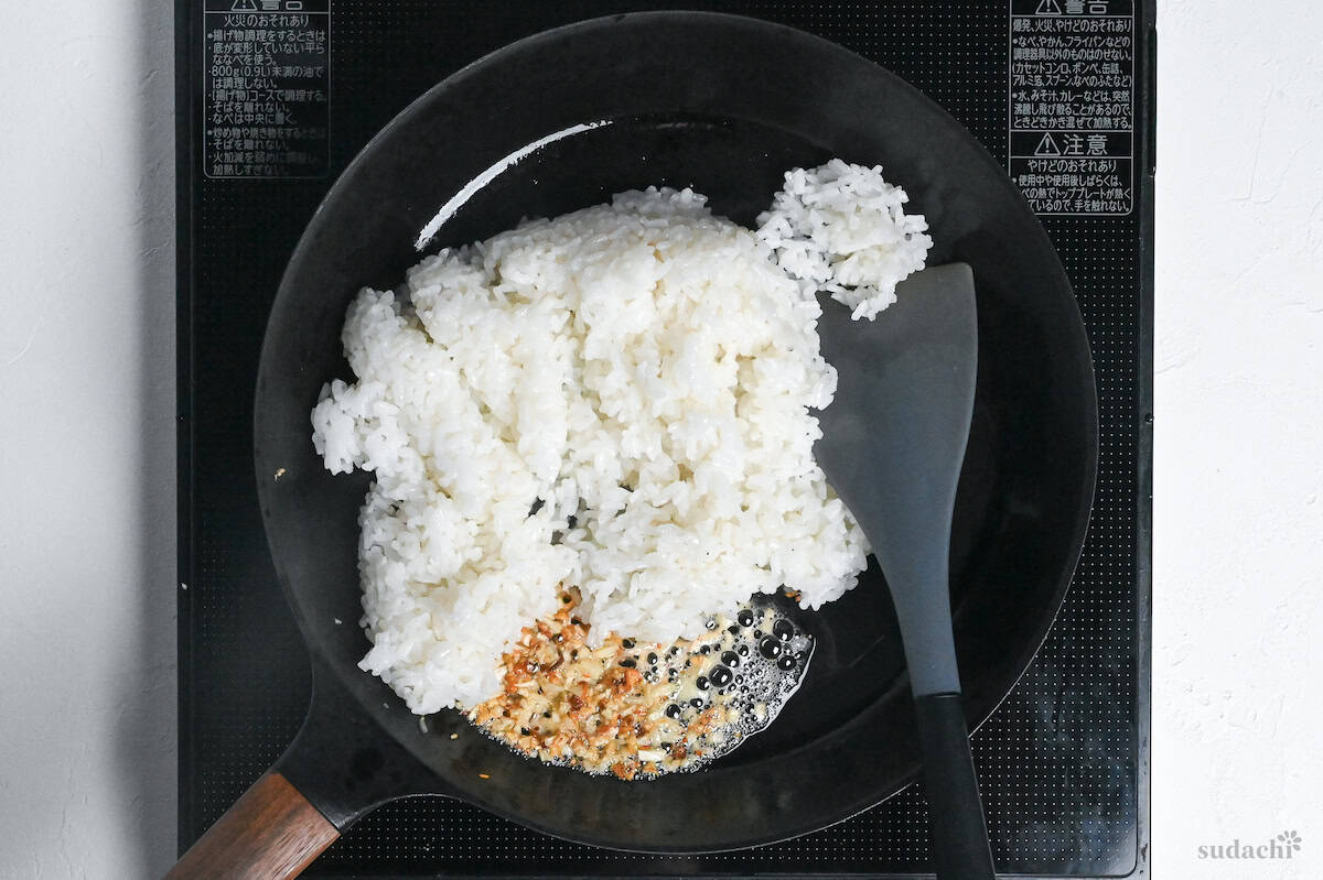 cooked rice added to a pan with fried garlic