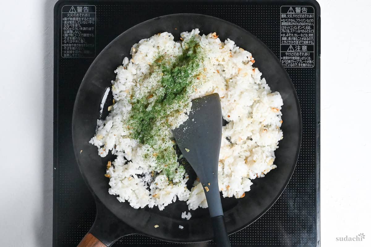 garlic rice with dry parsley in a frying pan on the stove