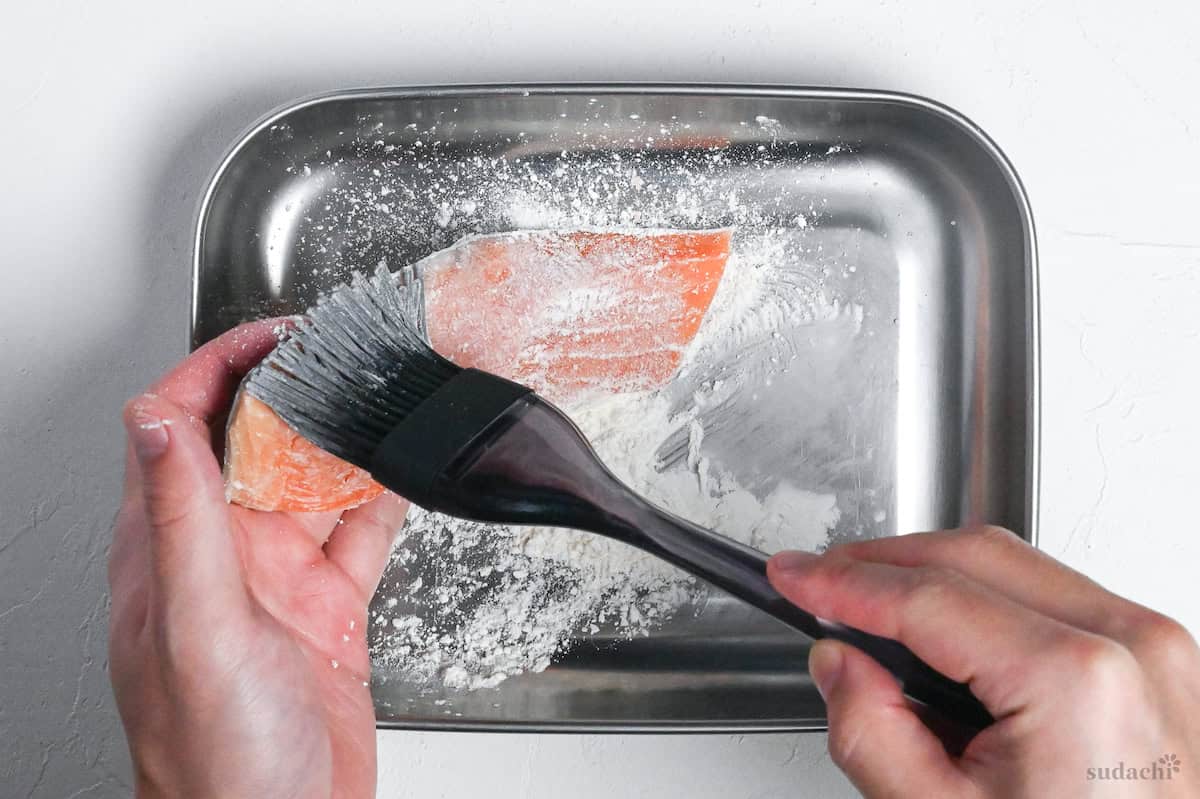 brushing salmon fillets with flour
