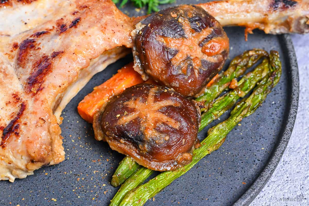 miso marinated roast vegetables next to pork chop on a gray plate