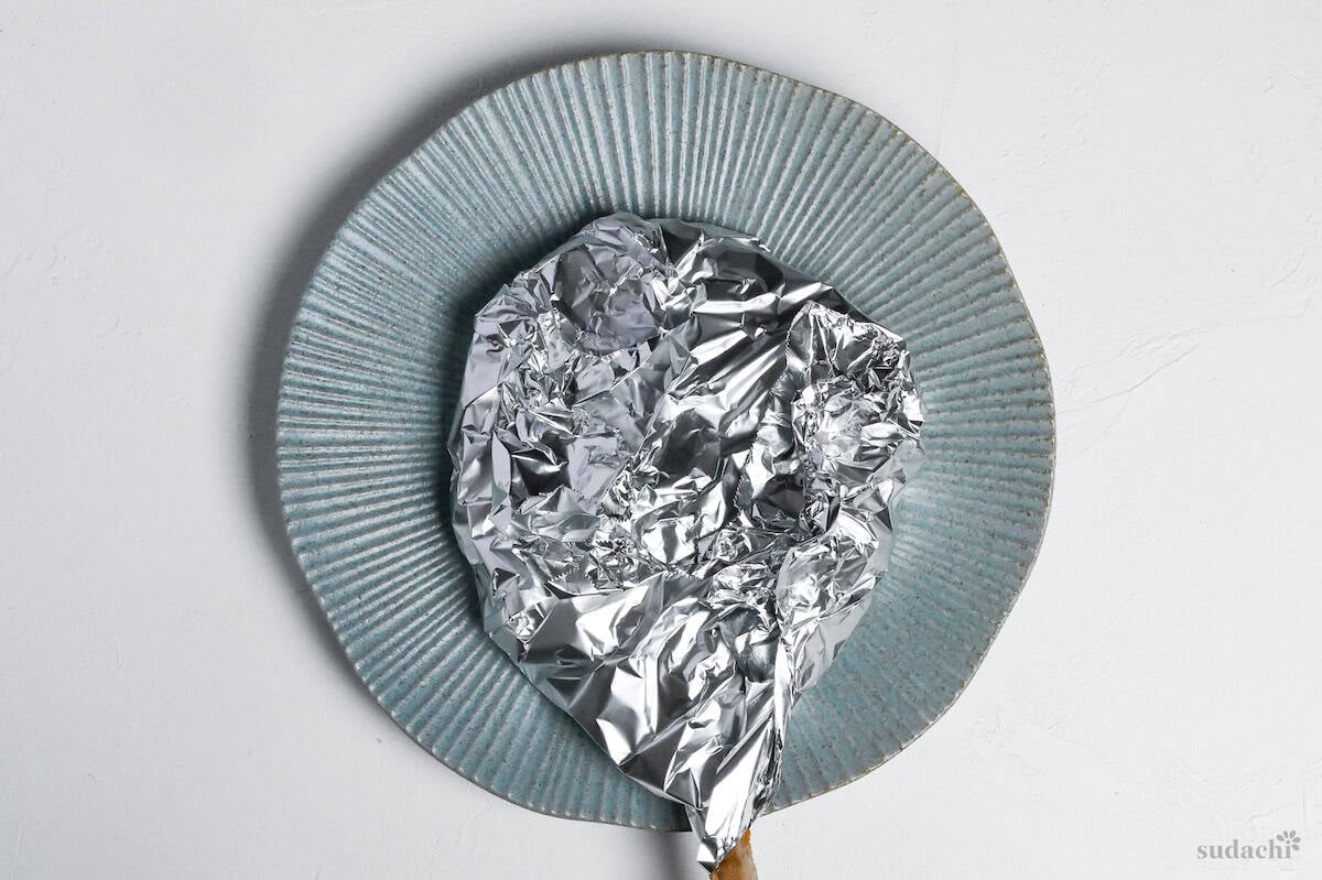 miso marinated pork chop wrapped with foil on a blue plate