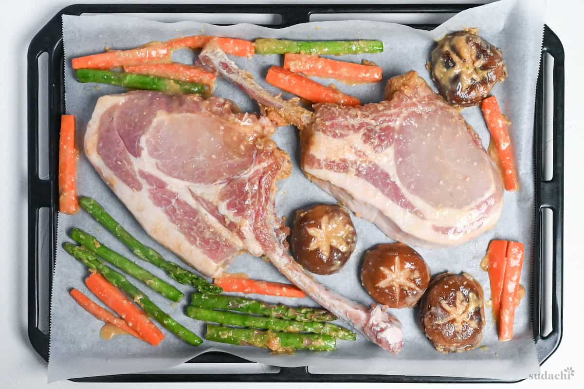 miso marinated pork chops and vegetables on a baking sheet lined with baking paper