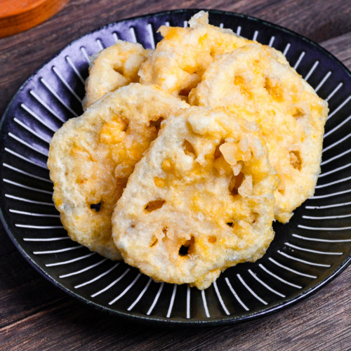 Five pieces of renkon tempura (lotus root) on a black plate with white stripes on a dark wooden background