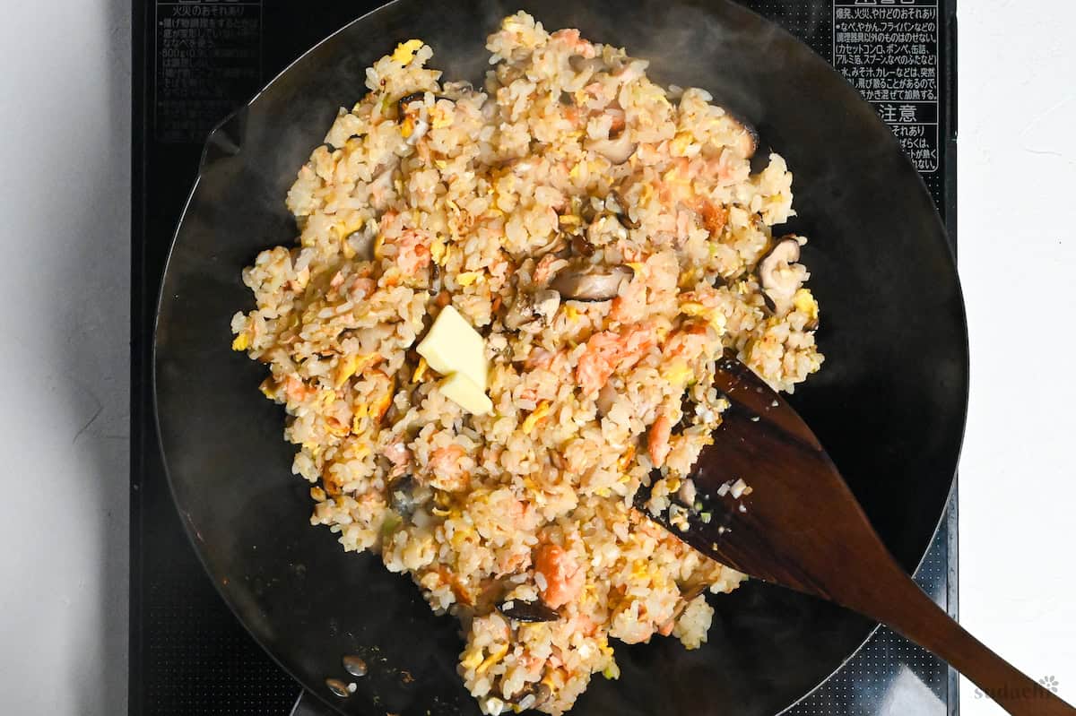 Salmon fried rice with butter in a wok on the stove top