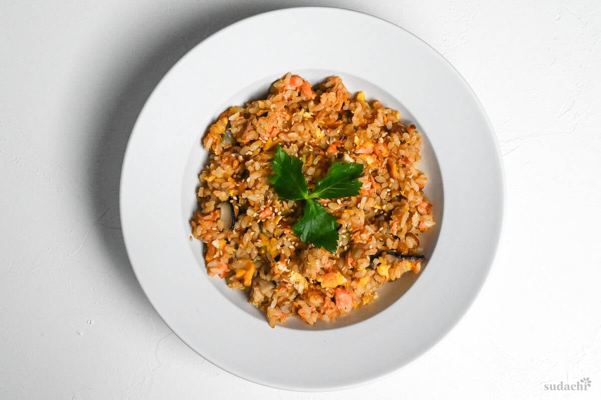 salmon fried rice in a white dish garnished with mitsuba (Japanese wild parsley)