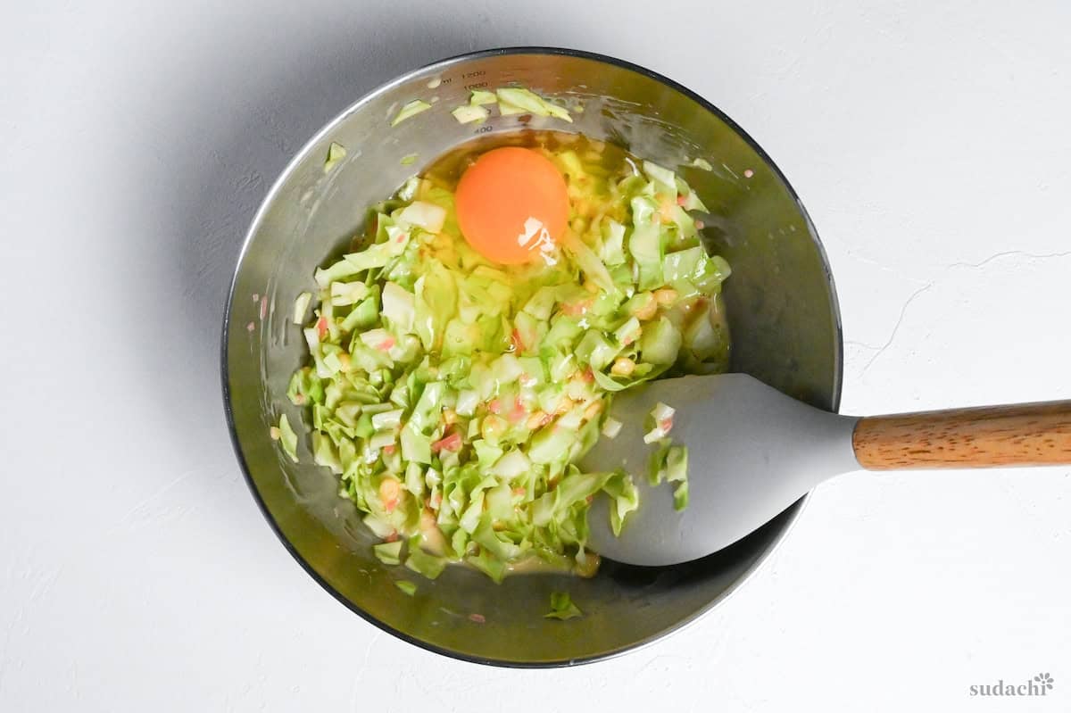 okonomiyaki batter in a mixing bowl with an egg and silicone spatula