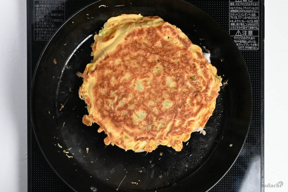 Flipped okonomiyaki showing crispy browned top
