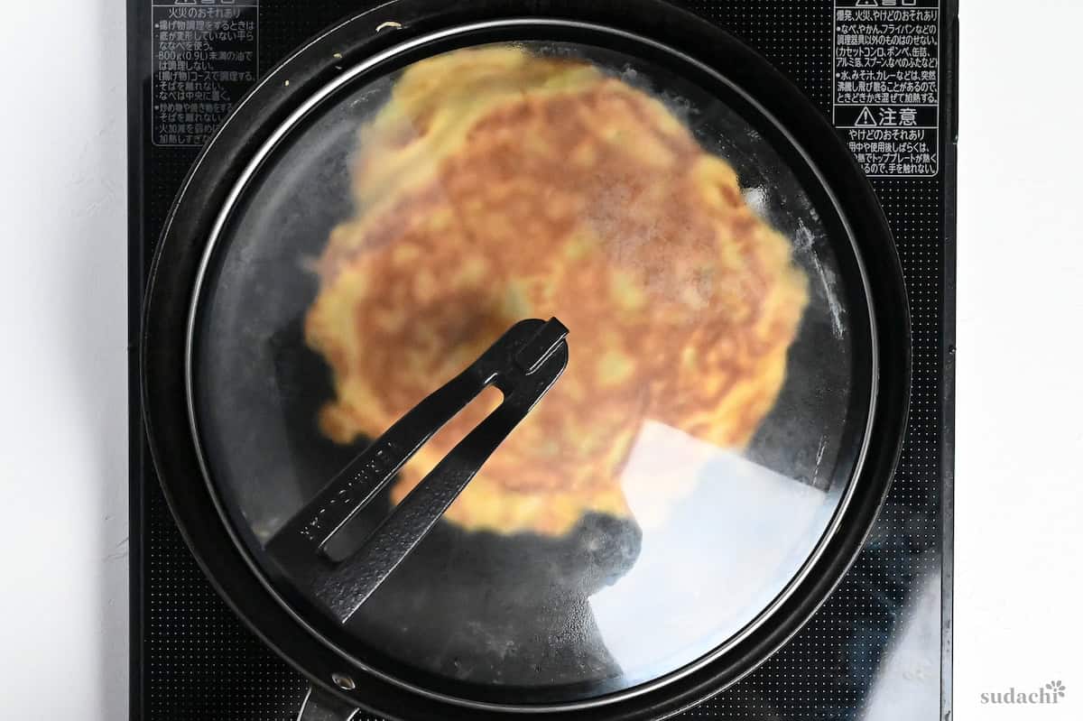 okonomiyaki in a pan with a lid on a stove top
