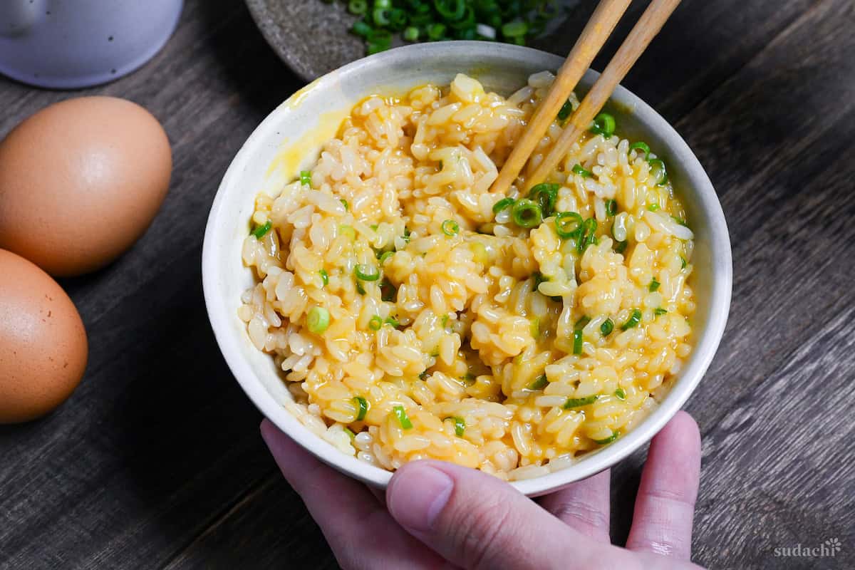 Tamago kake gohan mixed with chopsticks in a cream ceramic bowl