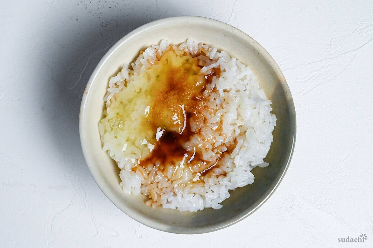 Raw egg yolk and seasonings on cooked rice in a ceramic Japanese rice bowl