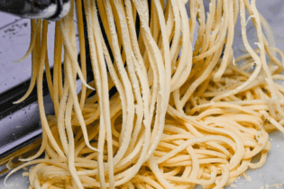 A close up of a pasta machine with spaghetti.