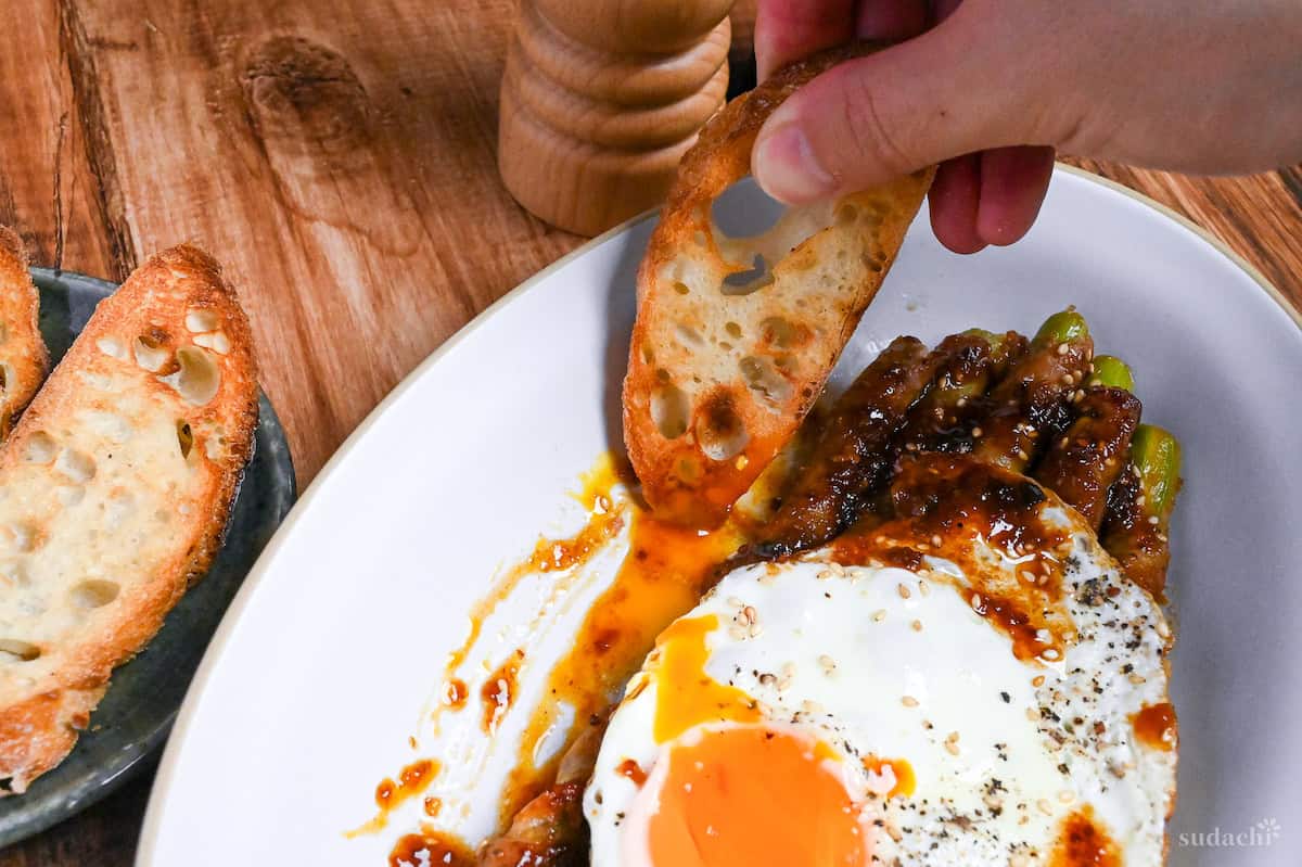 dipping baguette in runny egg and nikumaki asparagus sauce