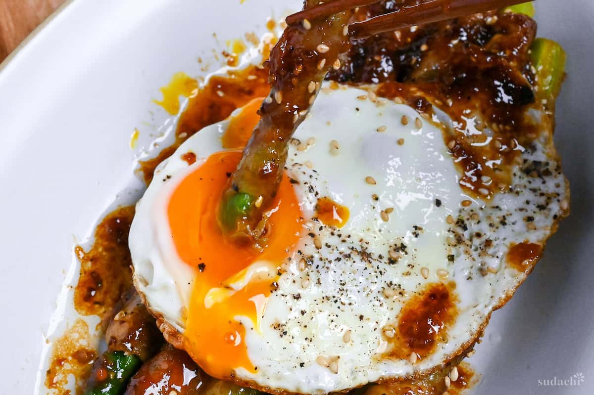 dipping nikumaki asparagus in runny yolk of sunny side up egg