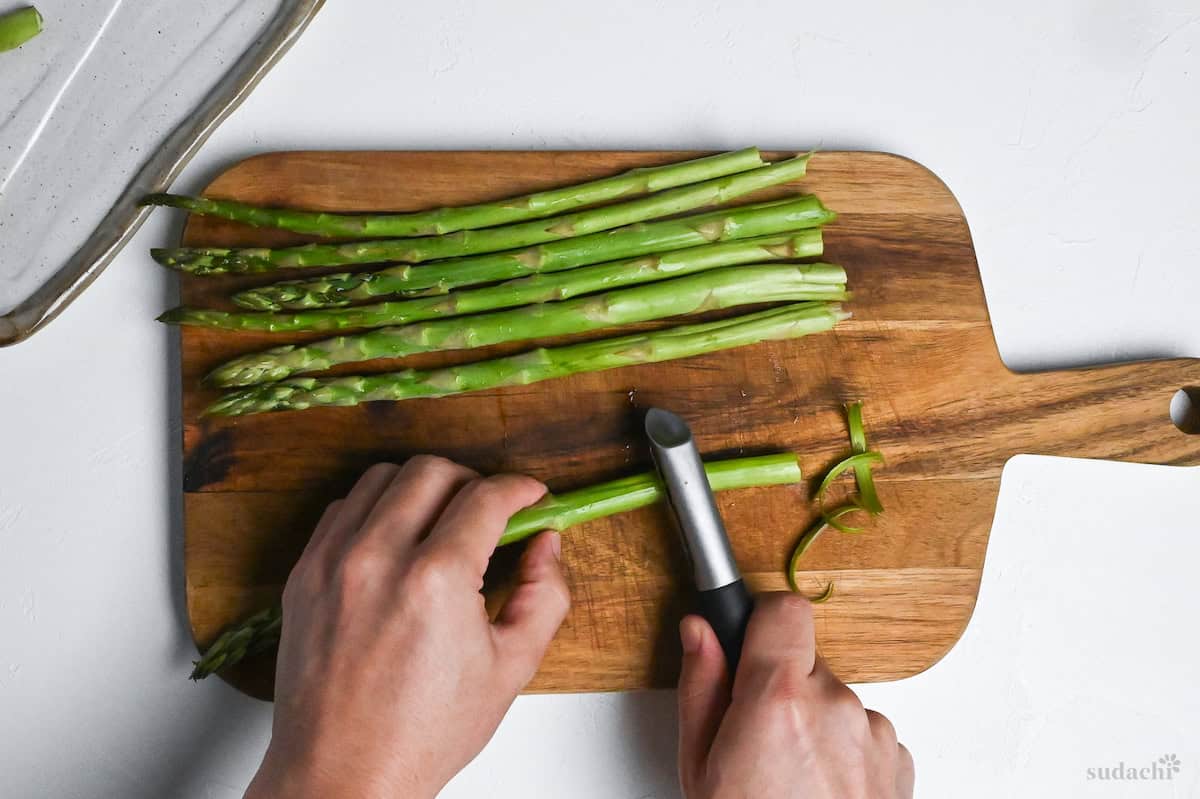 peeling base of asparagus stems with vegetable peeler