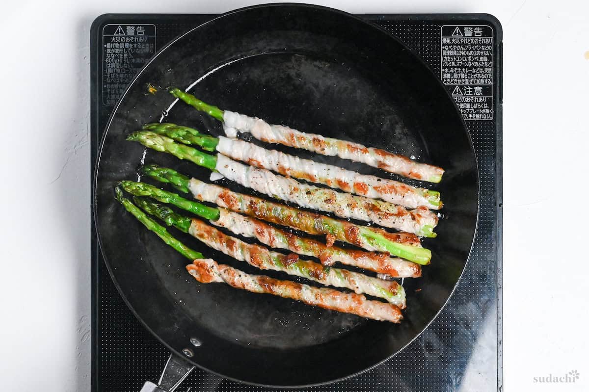 Nikumaki (pork belly wrapped) asparagus in a frying pan on the stove top