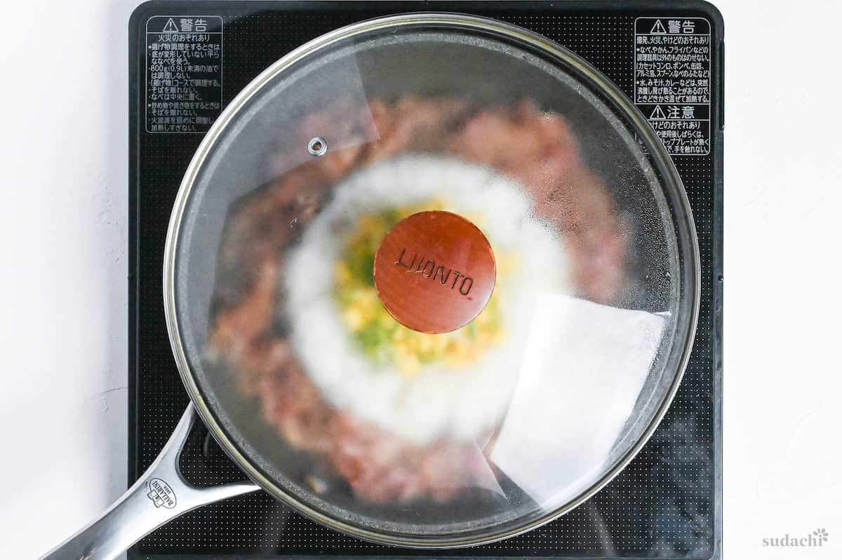 beef pepper rice in a frying pan covered with a lid on the stove top
