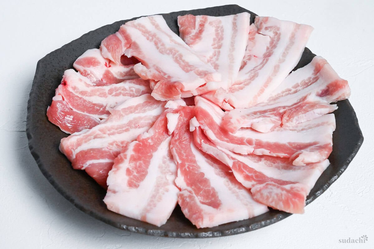thick slices of pork belly arranged on a brown plate on a white background