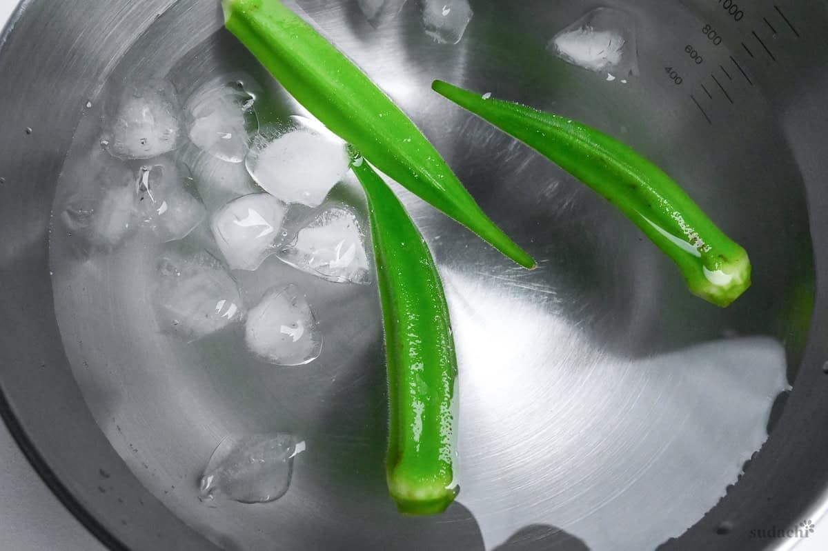 close up of 3 okra in a bowl of ice water