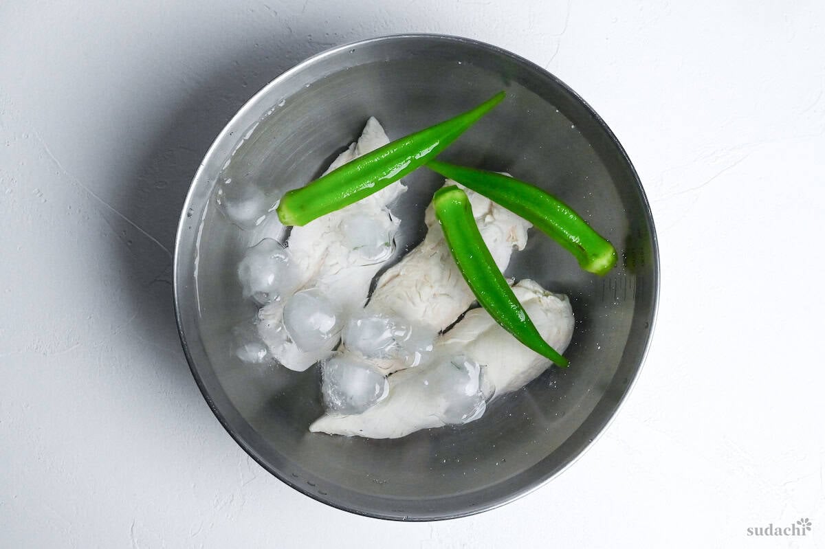 chicken tenders and okra in a bowl of ice water on a white background