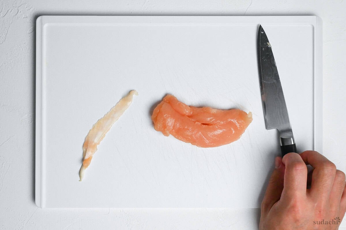 chicken tenderloin with tendon removed on a white cutting board