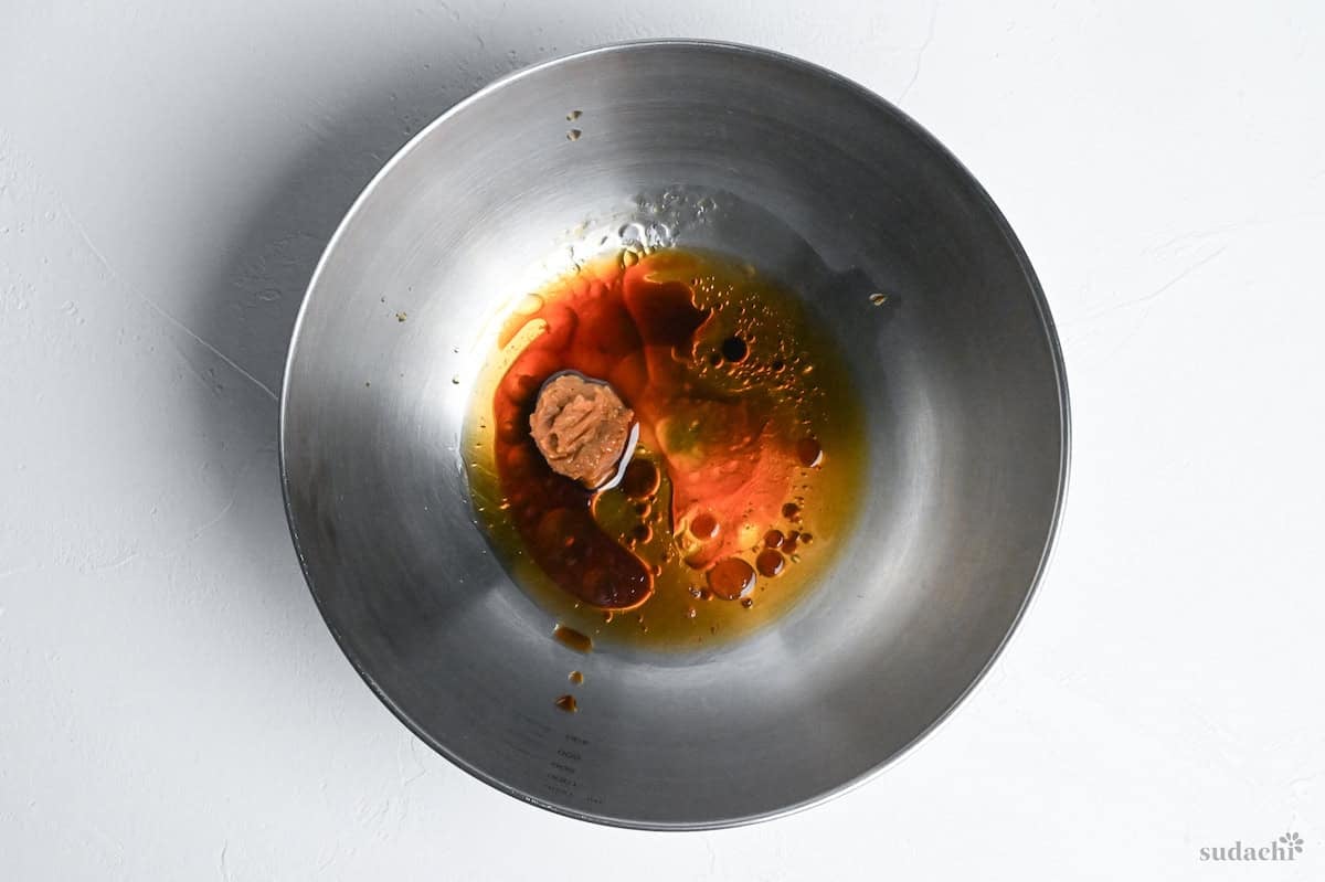 ingredients to make chicken tender salad Japanese style dressing in a steel mixing bowl on a white background