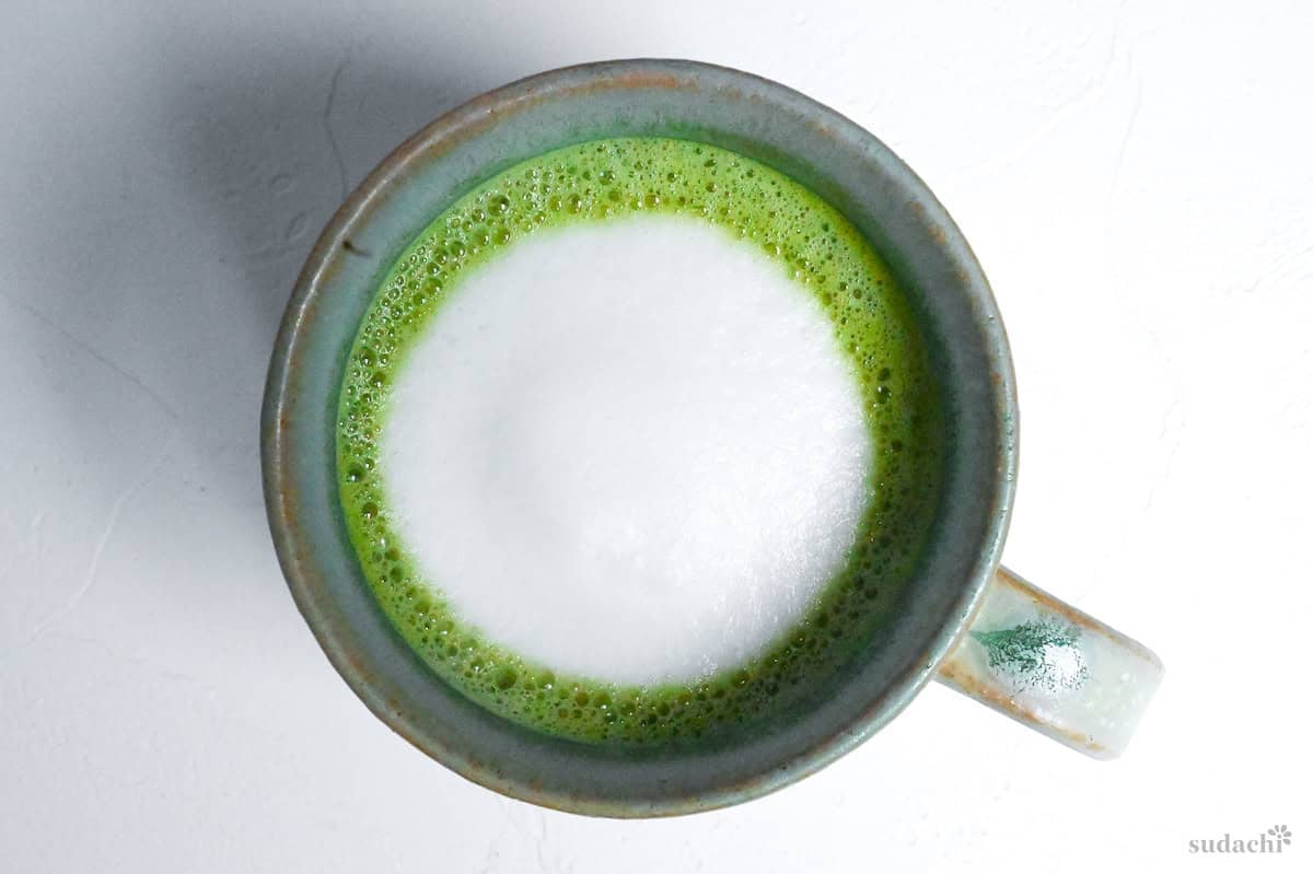 matcha latte with frothy milk in a teal colored ceramic cup