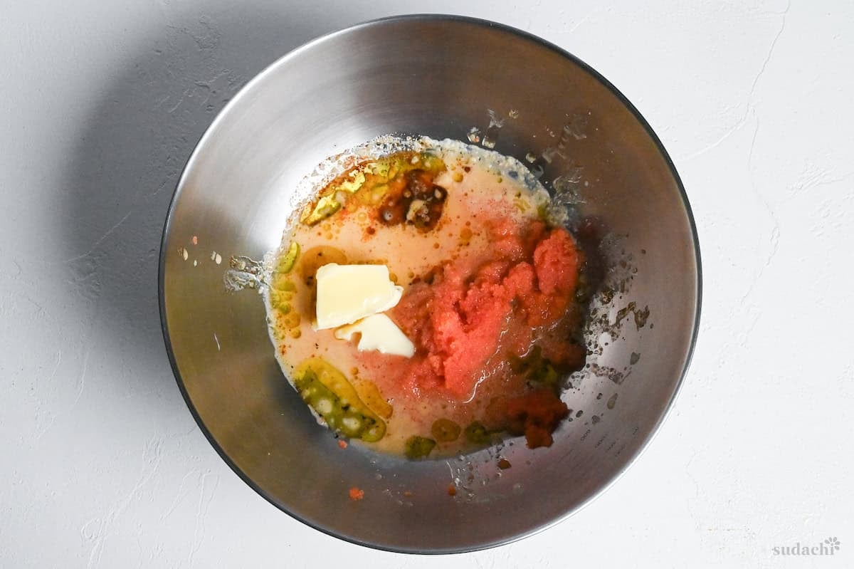 Ingredients for mentaiko pasta sauce in a mixing bowl on a white surface
