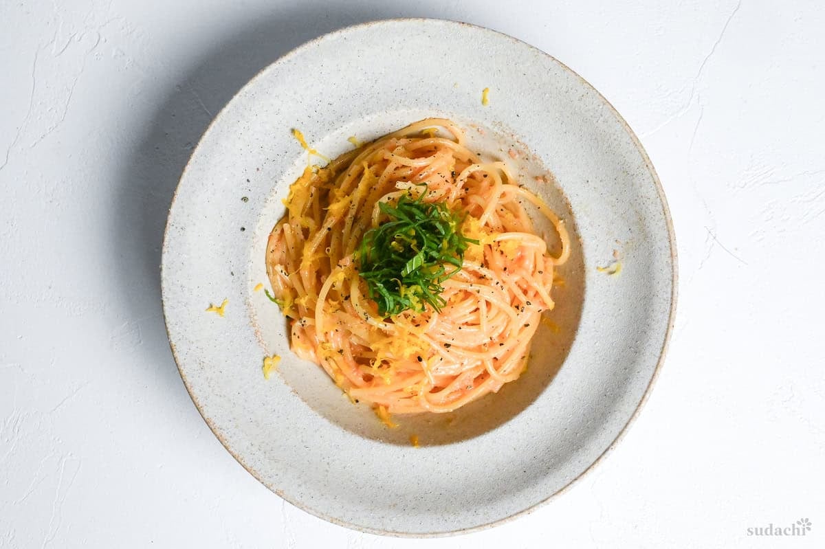 Mentaiko pasta in a cream dish topped with lemon zest and shredded Perilla leaves