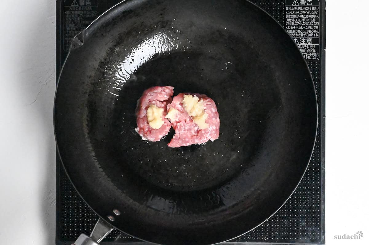 ground pork in a wok with grated garlic and ginger