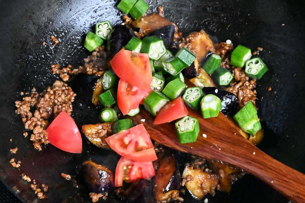 close up of miso ground pork cooking in a wok with summer vegetables