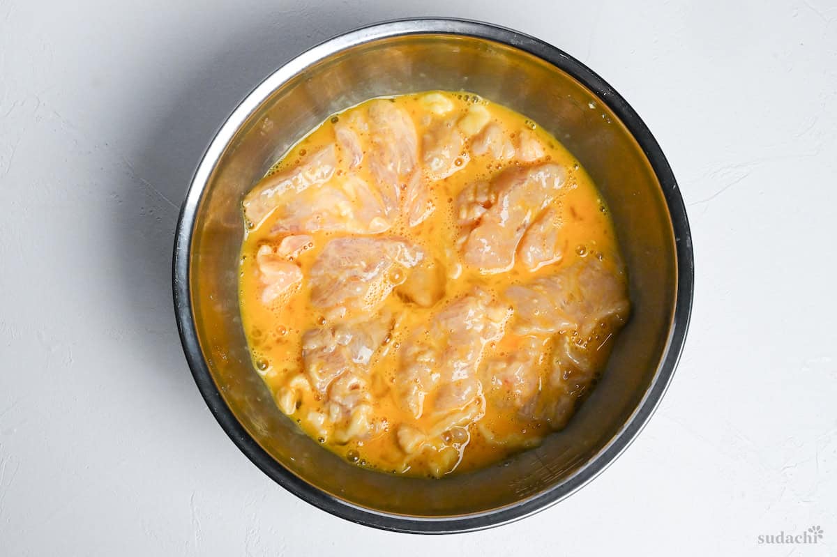 velveting chicken with egg and starch in a steel mixing bowl