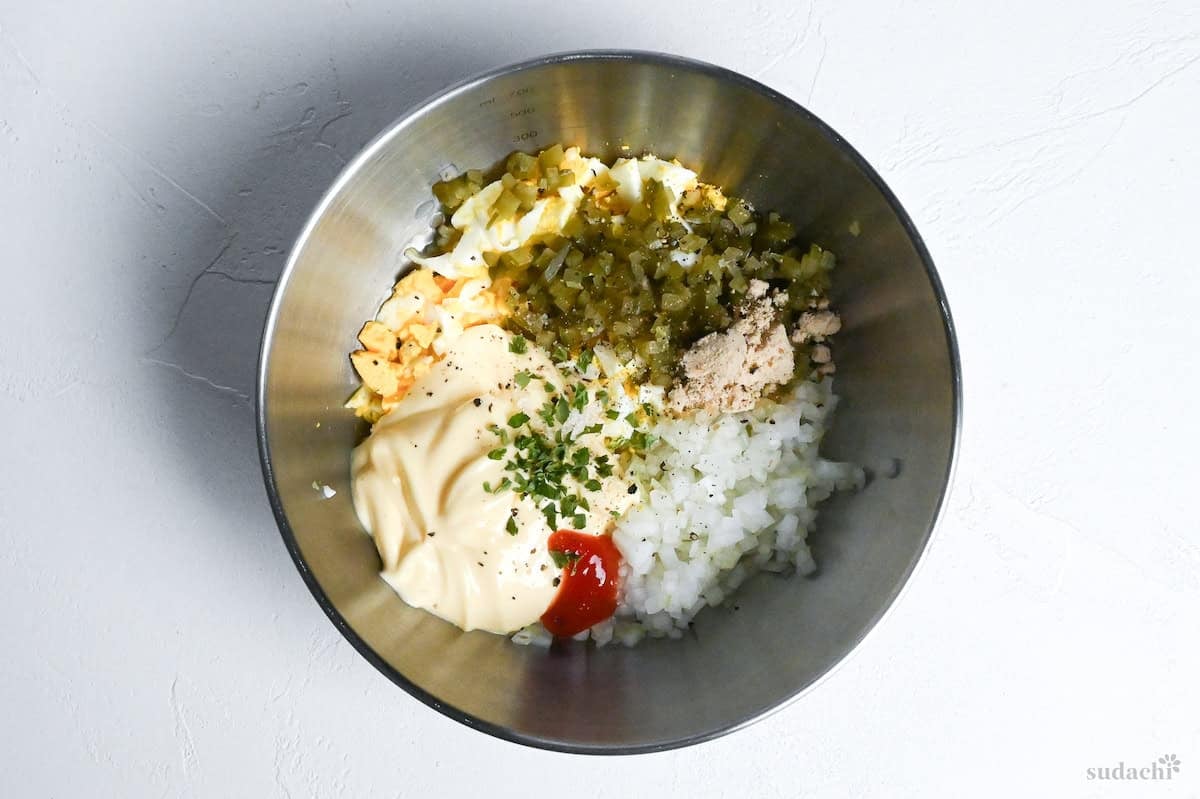 ingredients to make tartar sauce in a steel mixing bowl before mixing