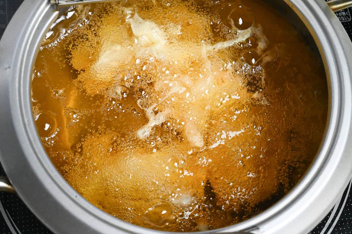 close up of chicken frying in oil