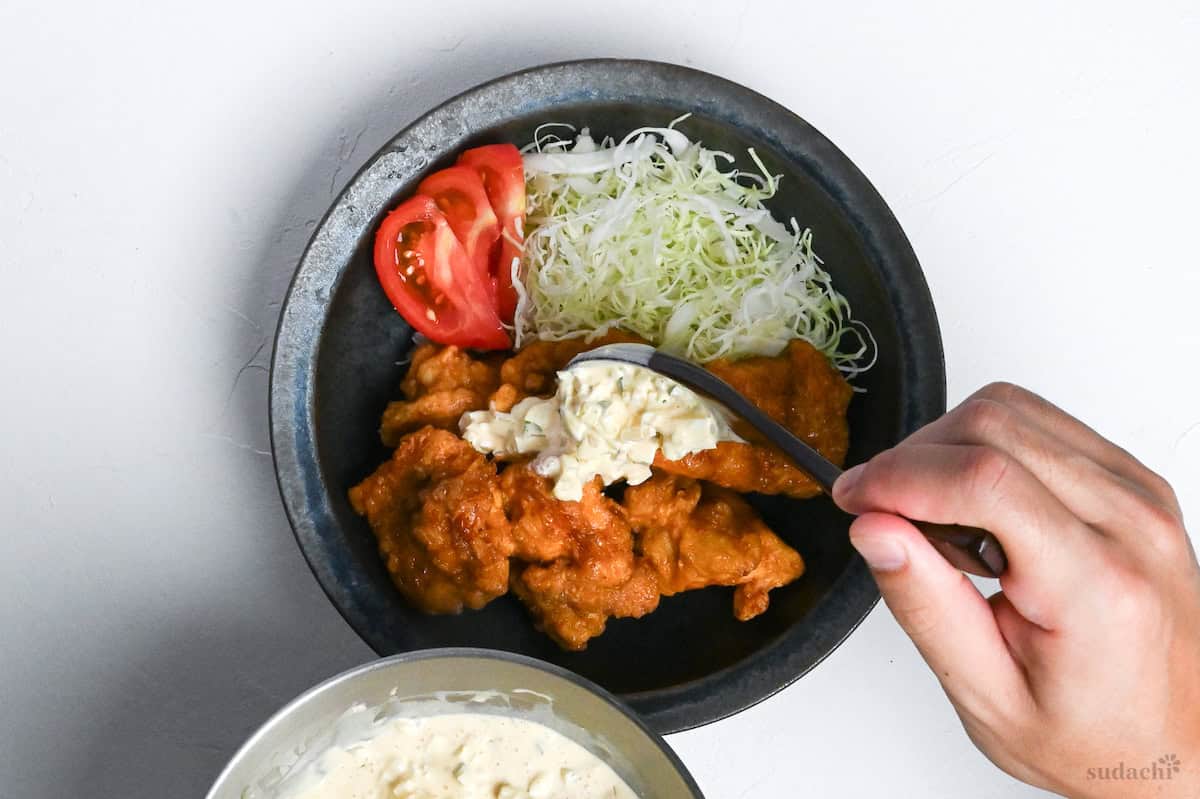 final plating of chicken nanban with shredded cabbage, tomato wedges and tartar sauce