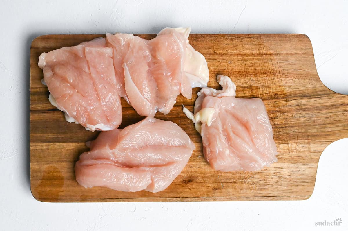 butterflied chicken breast cut into quarters on a wooden cutting board