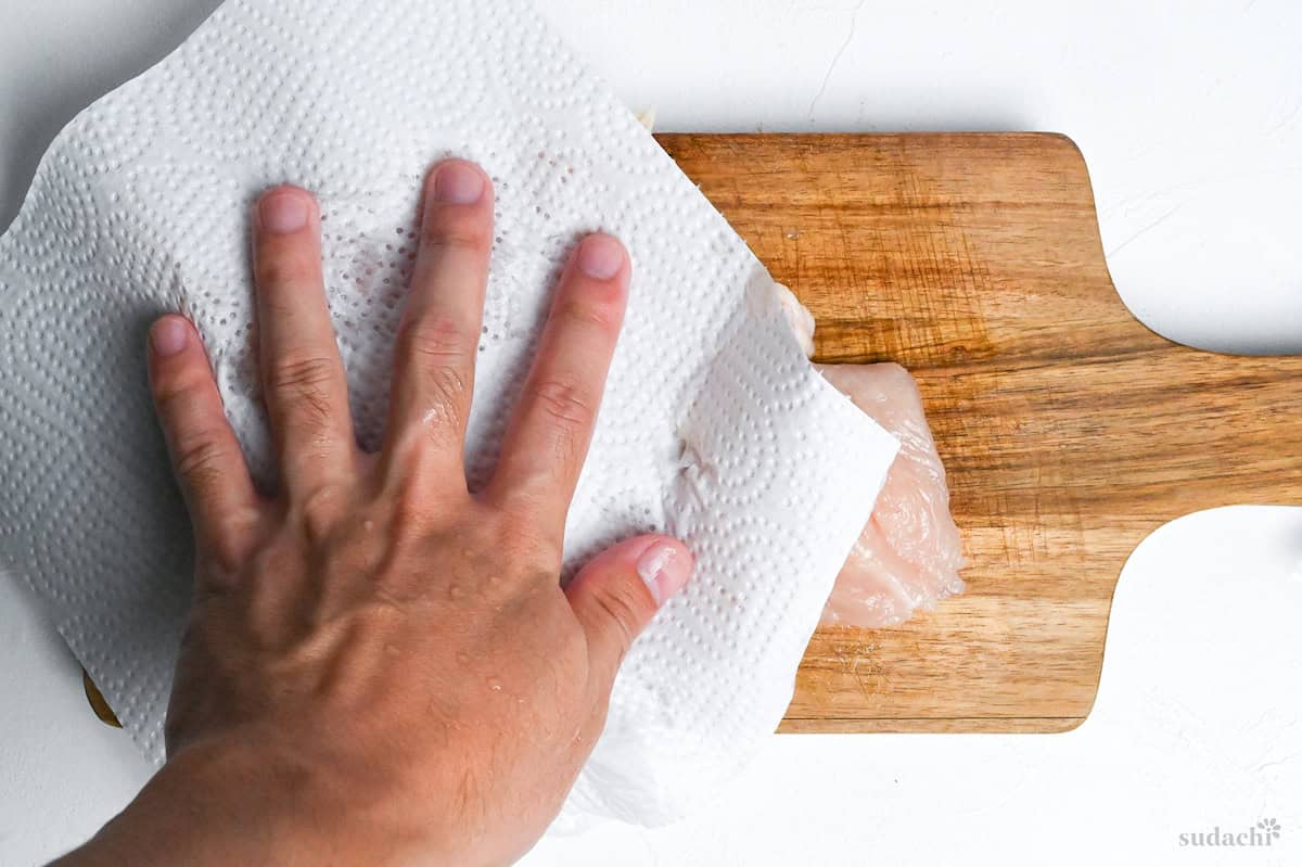 patting chicken dry with kitchen paper
