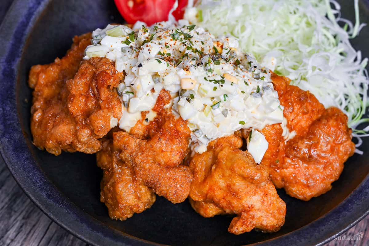 final plating of chicken nanban with shredded cabbage, tomato wedges and tartar sauce
