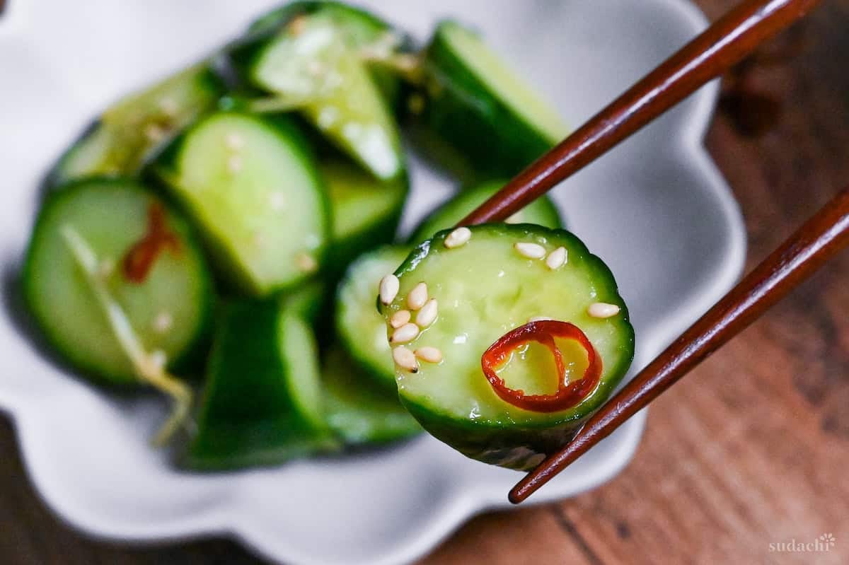pickled cucumber with ginger held with wooden chopsticks