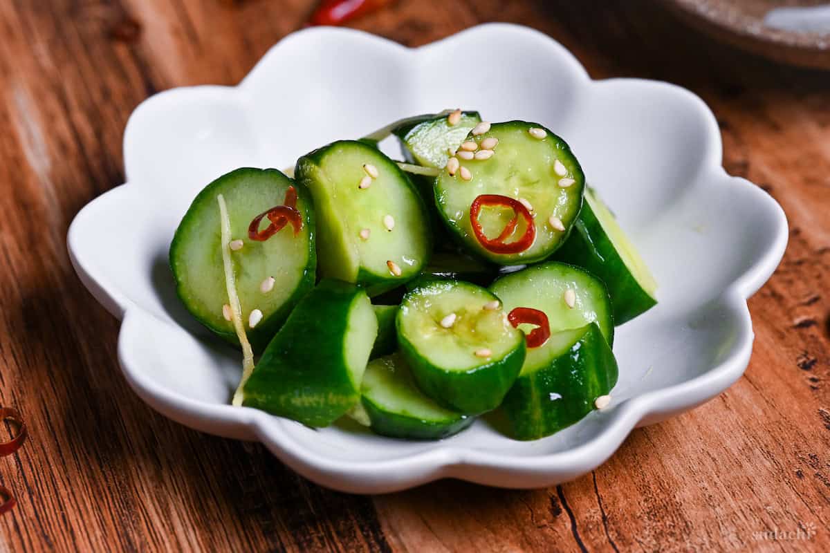 Complete Japanese pickled cucumber with ginger and chili sprinkled with sesame seeds in a small white serving dish