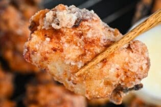 close up of complete double fried shio koji karaage Japanese fried chicken held up with chopsticks