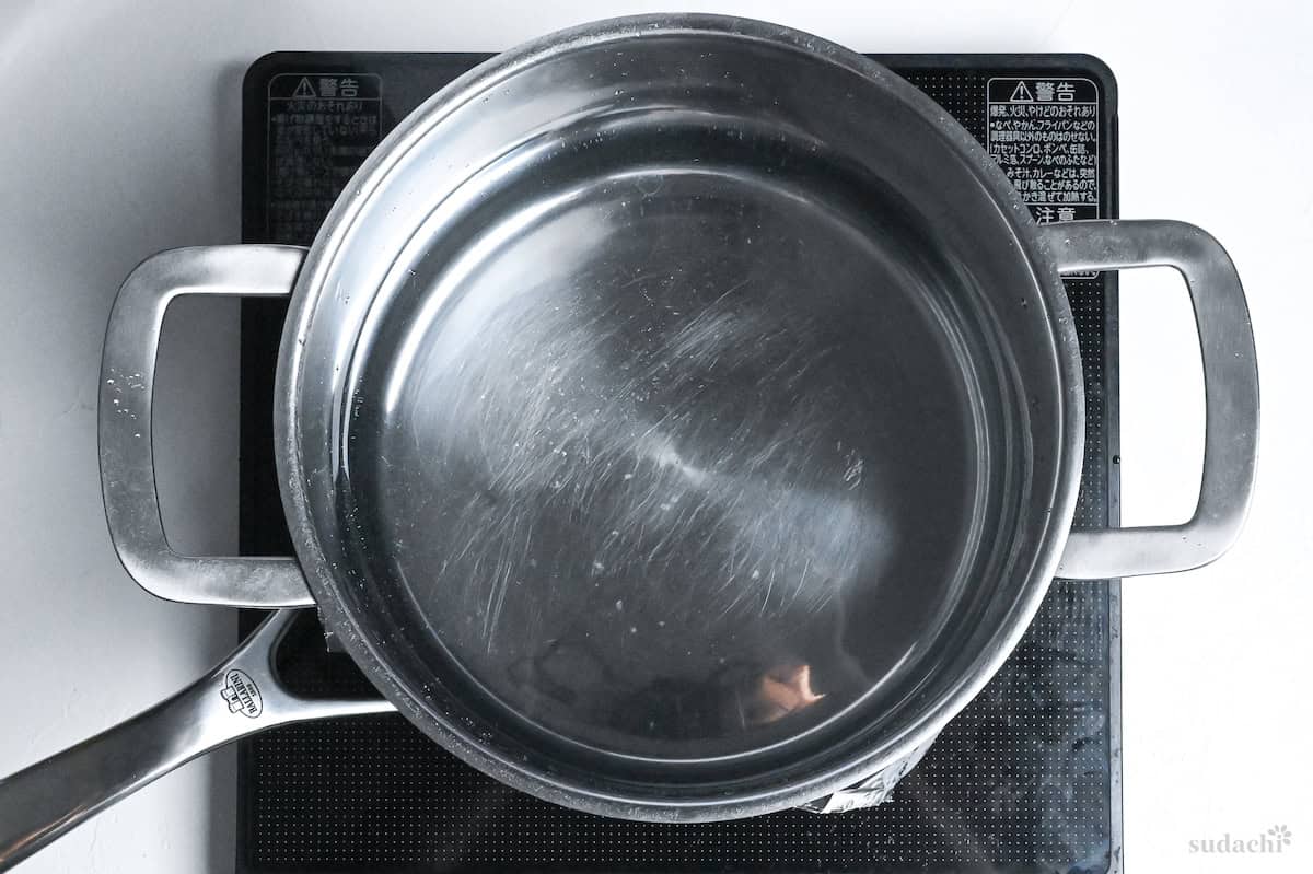 a pot of water on top of foil weighing down chicken thighs in a pan on the stove top