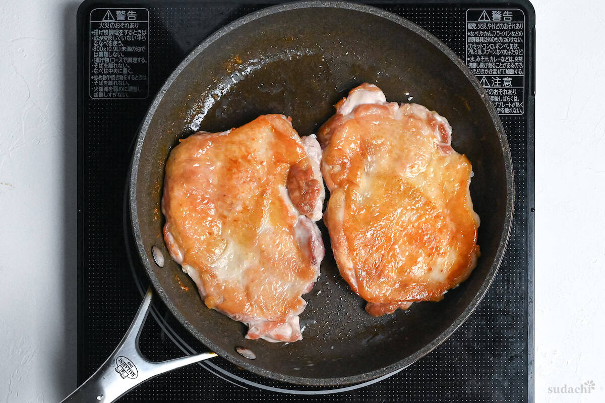 crispy chicken thighs in a frying pan on the stove top