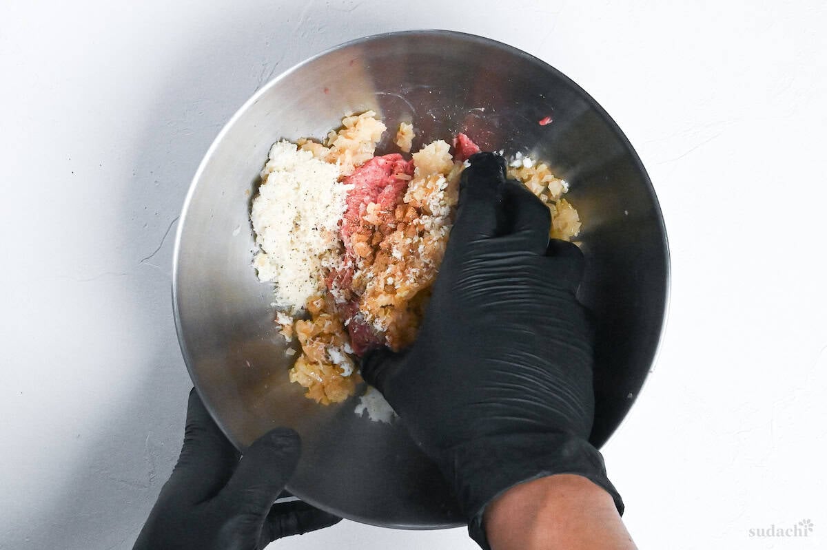kneading hamburg mixture by hand in a steel bowl