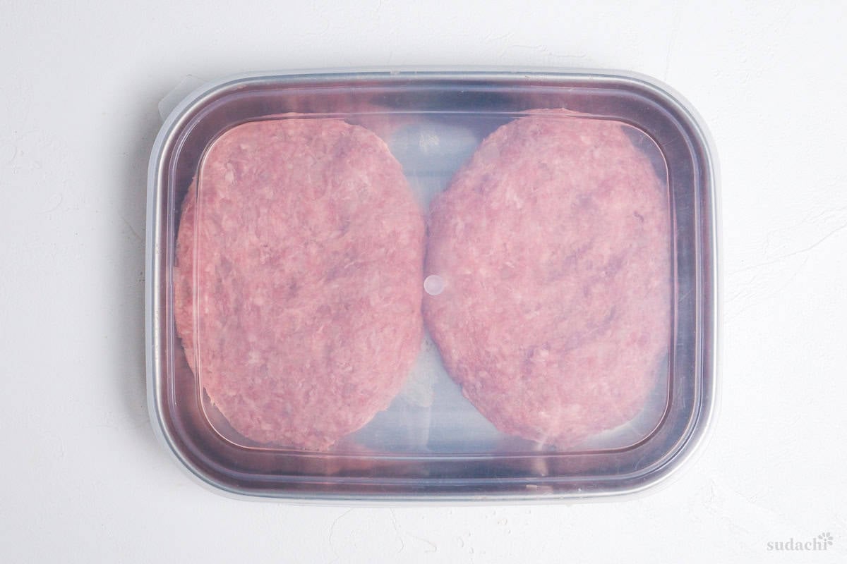 two hamburg patties in a container with lid