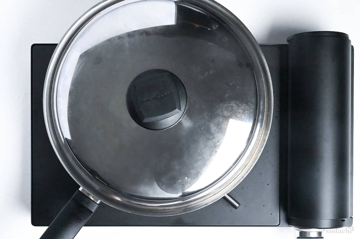 a stainless steel pan on the stove top with lid on