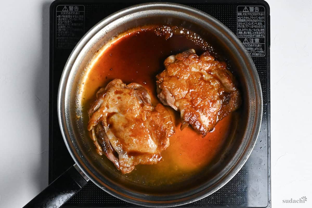 thickened teriyaki sauce over chicken thighs in a stainless steel pan