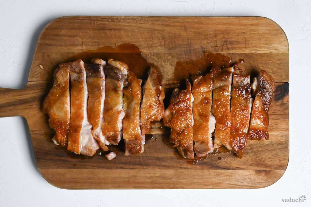 teriyaki chicken thighs cut into strips on a wooden cutting board