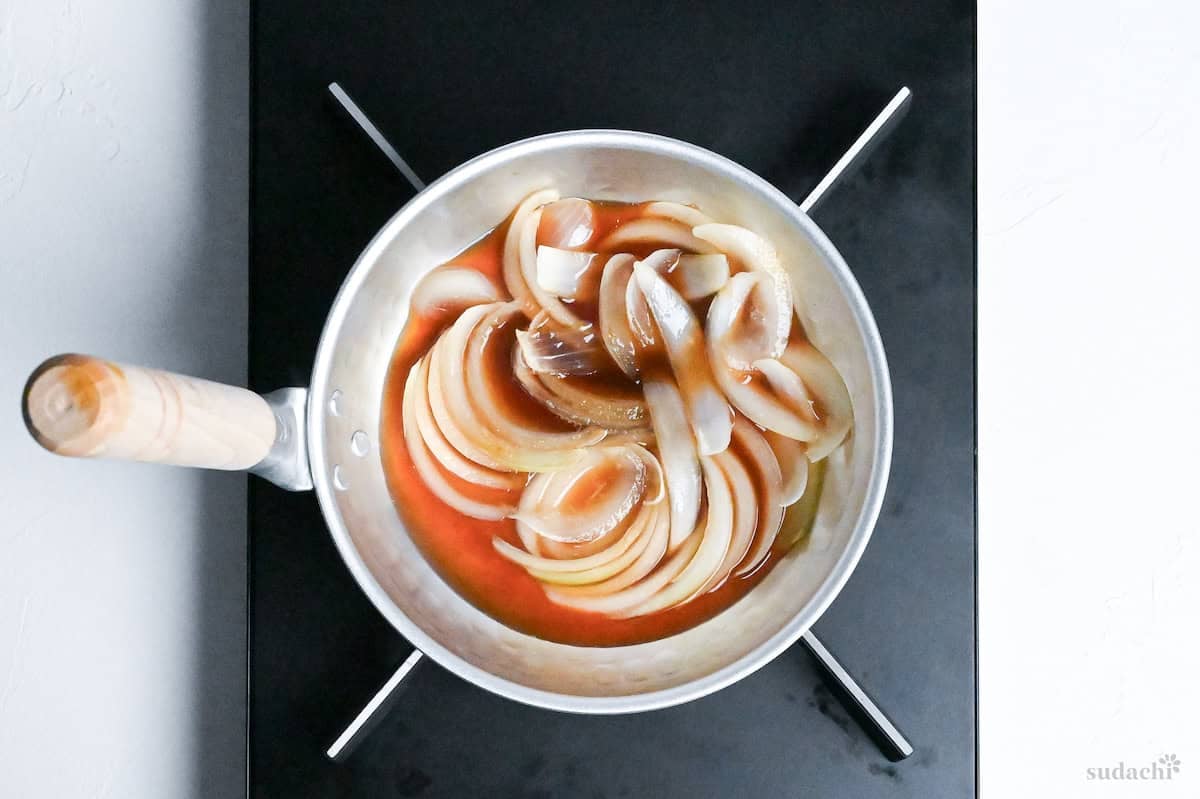onion slices simmering in dashi in a Japanese style pan